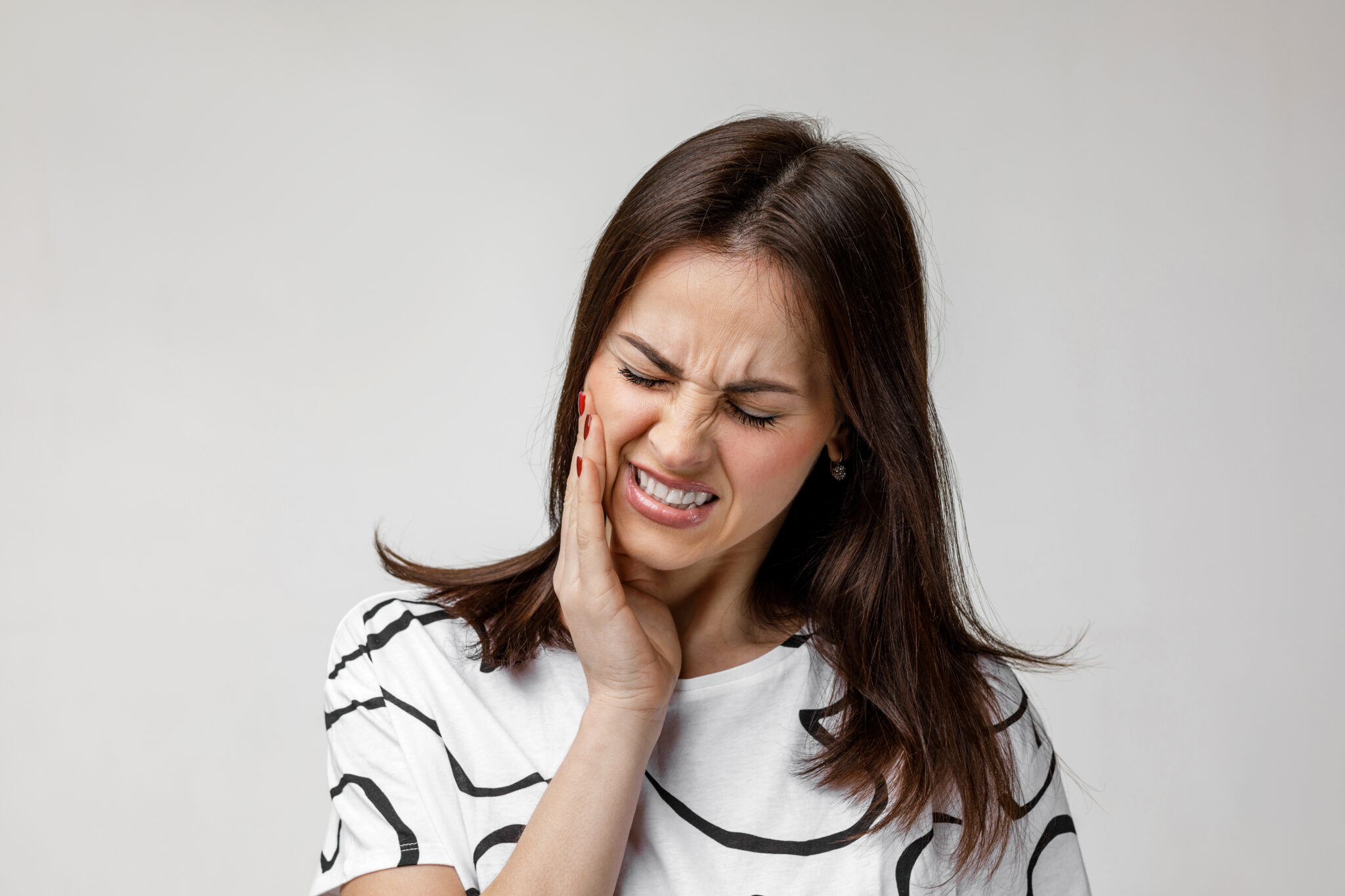 Protect Against Gum Disease Slide - A woman wincing in pain and holding her jaw with her right hand.